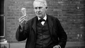 Thomas Edison sostiene una bombilla.