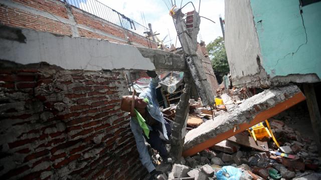 Un hombre observa los escombros de su casa.