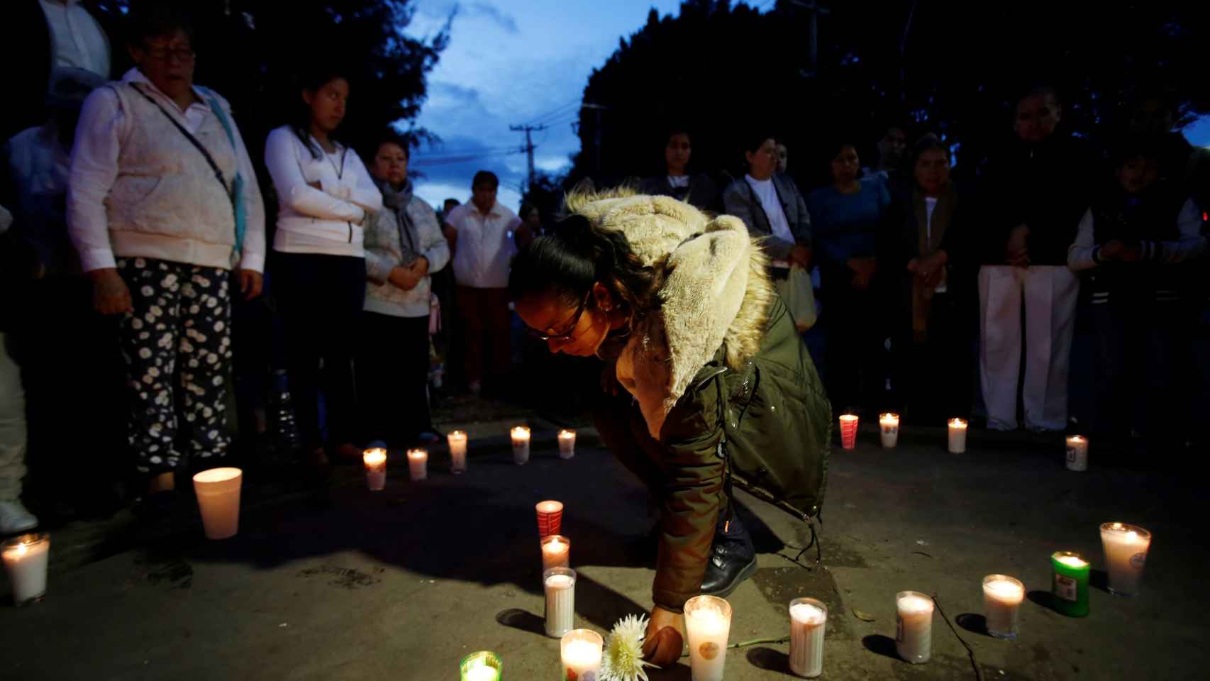 Una mujer coloca velas en memoria de los fallecidos en el seísmo.