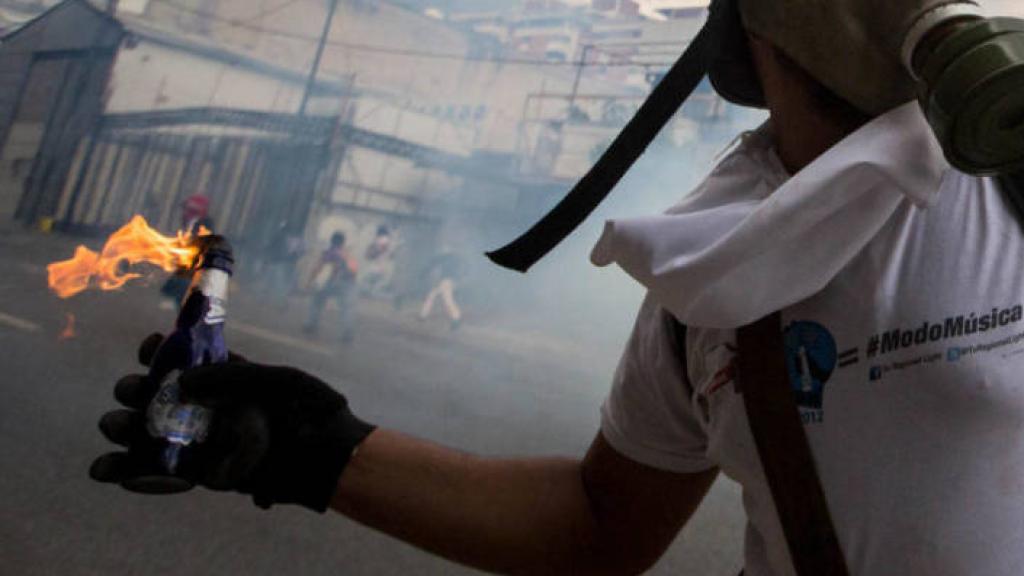 Un hombre lanza un cóctel Molotov en una manifestación.