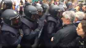 Un grupo de policías nacionales forcejea con una multitud ante el colegio Ramón Llull de Barcelona.