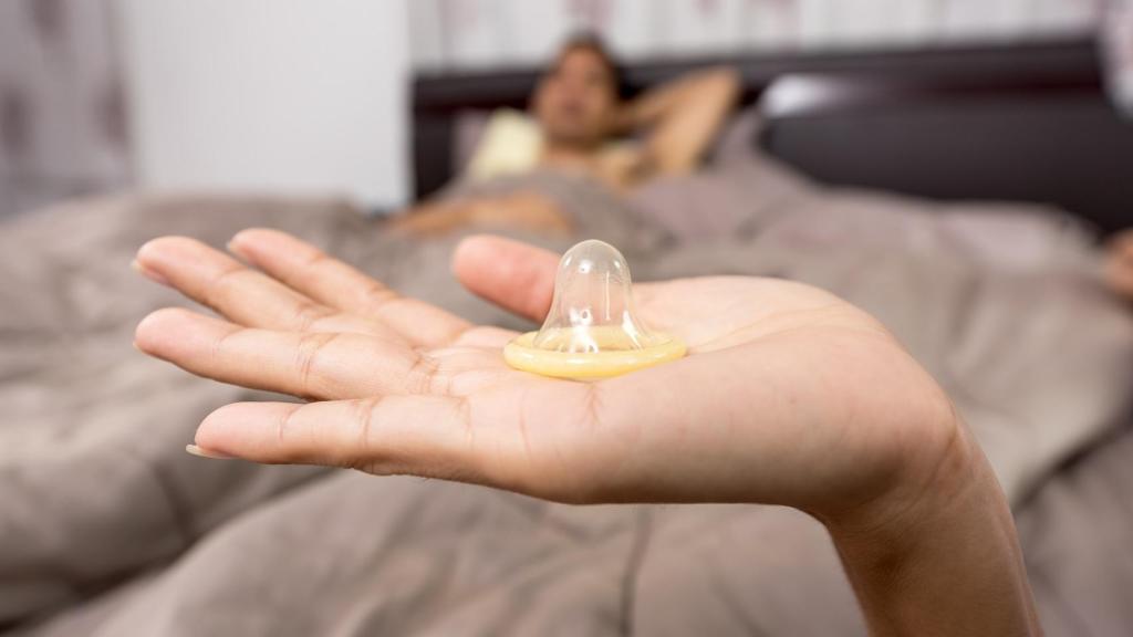 Una mujer sostiene con la mano un preservativo.