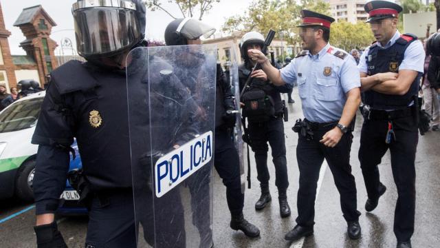 Agentes antidisturbios de la Policía Nacional y de los Mossos d' Esquadra discuten durante el 1-O.