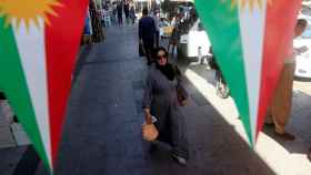 Una mujer camina en la calle, entre pancartas que apoyan el referéndum para la independencia del Kurdistán en Erbil.