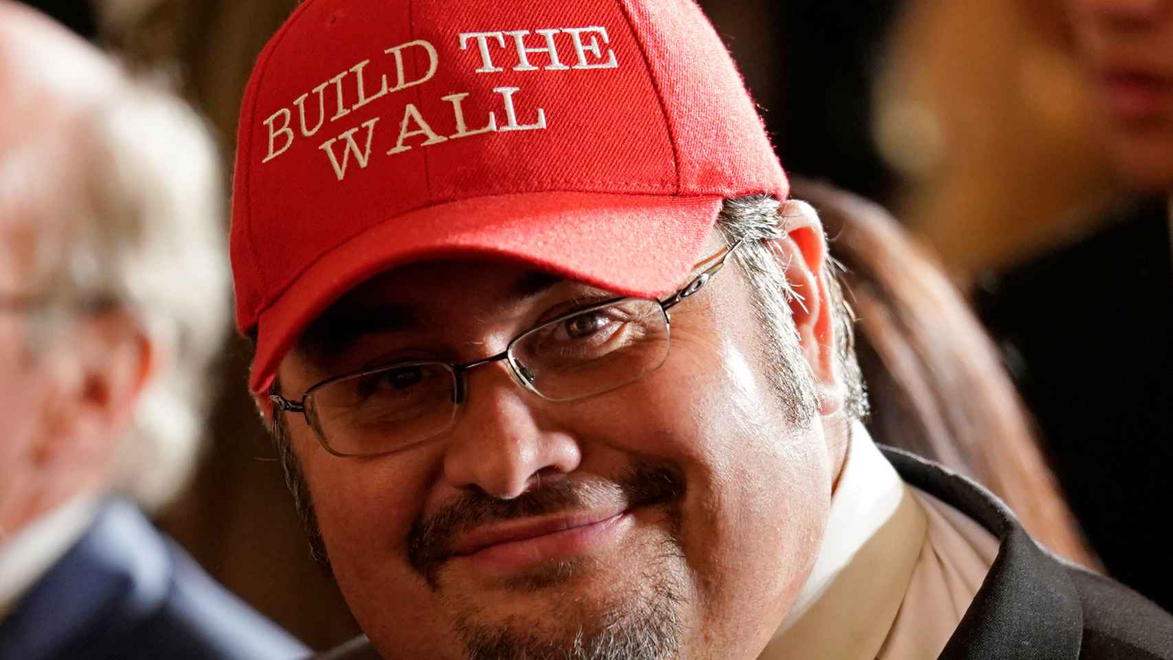 Freddy Burgos, del partido republicano, con una gorra en  defensa del muro de Trump.