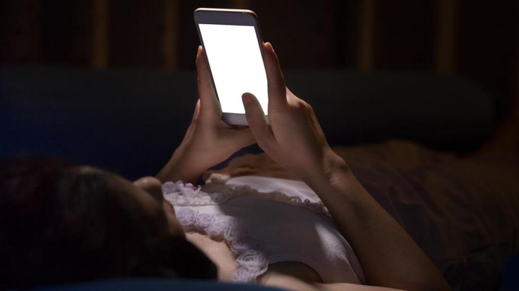 Una mujer usando el móvil en la cama.