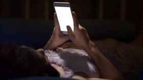 Una mujer usando el móvil en la cama.