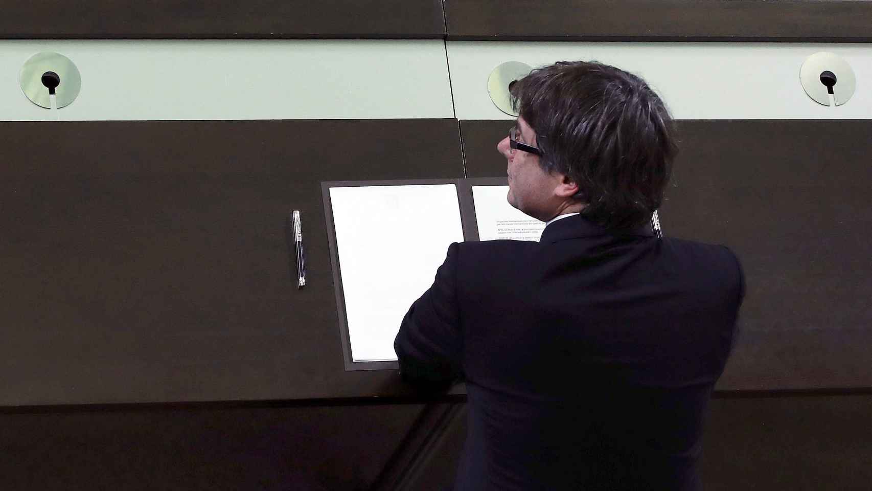 El presidente de la Generalitat, Carles Puigdemont, firma el documento sobre la Independencia después de comparecer ante el pleno del Parlament para trasladar los resultados de la jornada del 1-O. EFE/Alberto Estévez