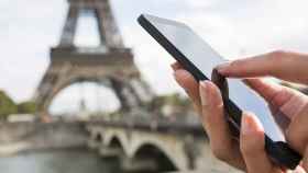 Una persona utilizando su teléfono móvil junto a la Torre Eiffel de París