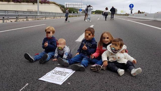 Cinco niños sentados en el tramo de la carretera C-32 a la altura de Mataró (Barcelona).