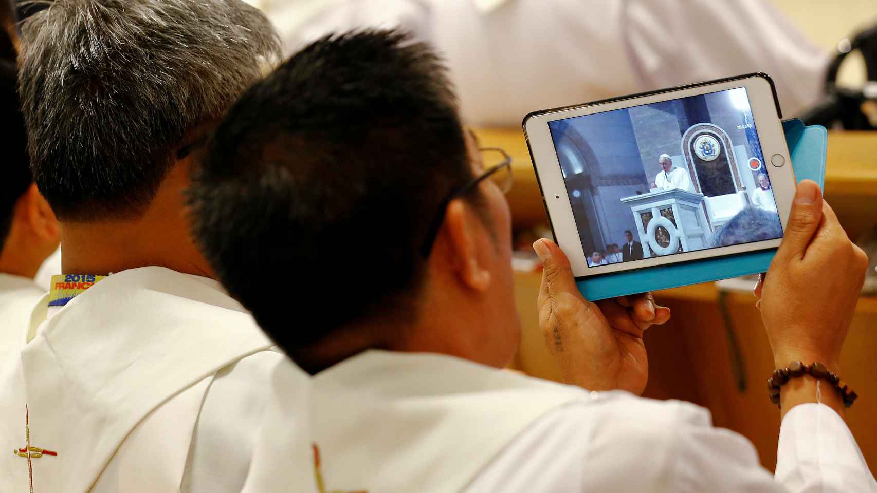 Un sacerdote, haciendo fotos con su tablet.