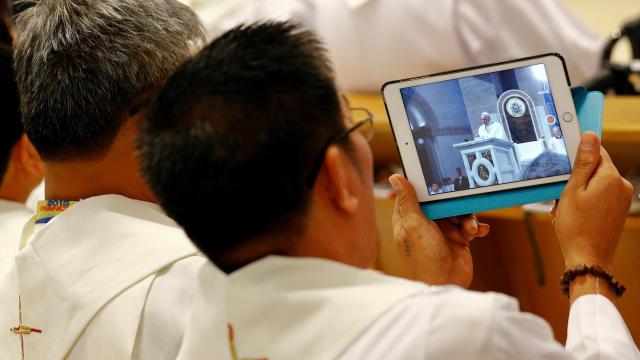 Un sacerdote, haciendo fotos con su tablet.