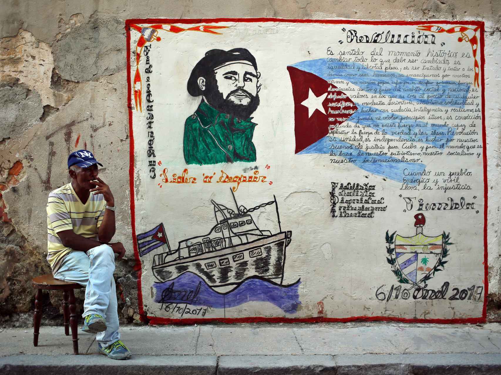 Un cubano fuma junto a una pintada con la imagen de Fidel Castro en La Habana.