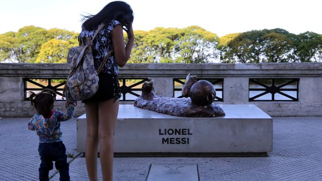 Una turista se para en la estatua de Messi.