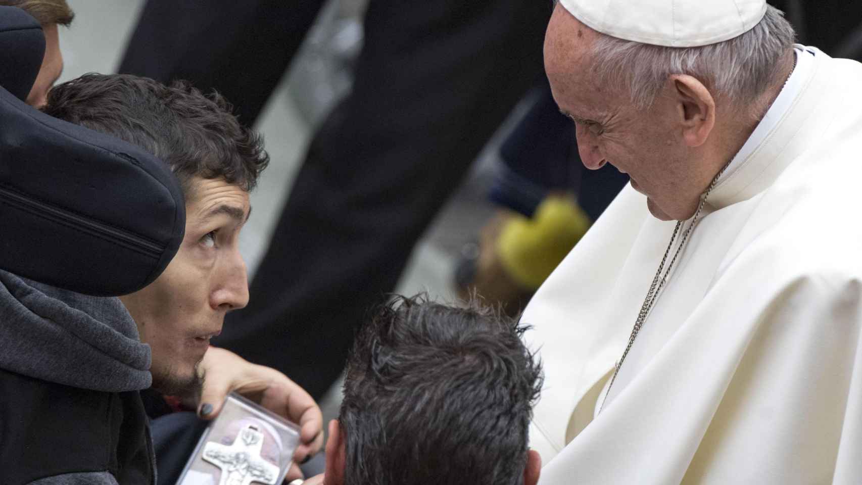 El papa Francisco recibe una cruz como presente tras su tradicional audiencia general de los miércoles.