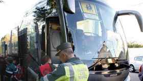 Un guardia civil revisa los papeles de un autobús de transporte escolar en Torrejón de la Calzada (Madrid).