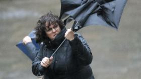 Un mujer trata de sujetar su paraguas en Santiago de Compostela