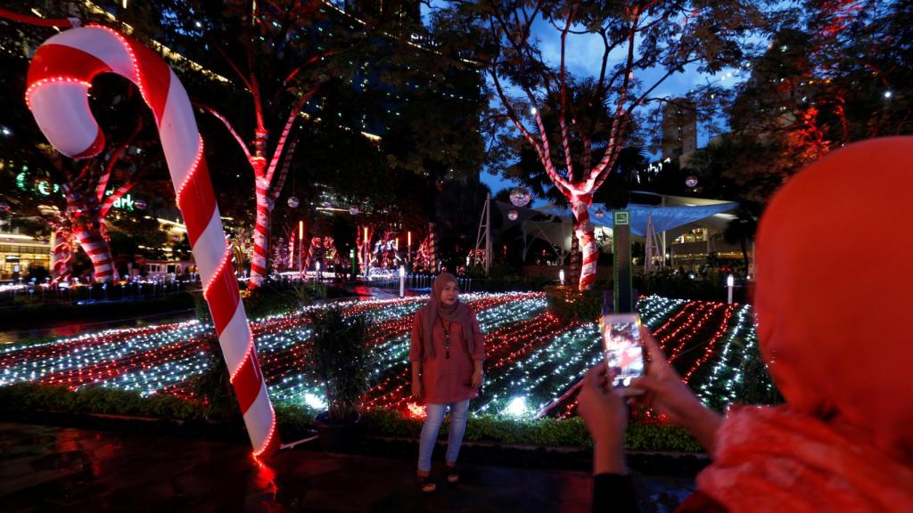 Una mujer musulmana en Yakarta haciendo fotos en un parque con adornos navideños.