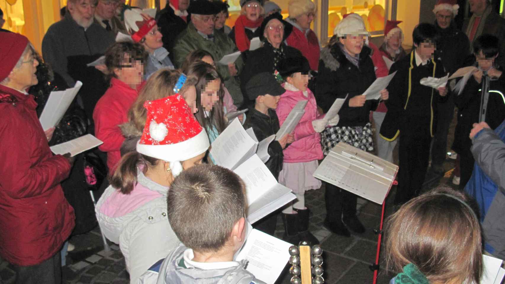 Un grupo de personas cantan villancicos navideños.