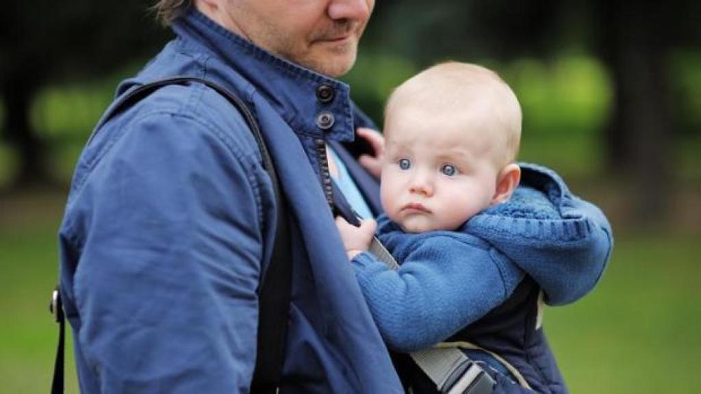 Un padre pasea a su bebe recién nacido.