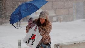 Una mujer cruza una calle de Nueva York  bajo el temporal