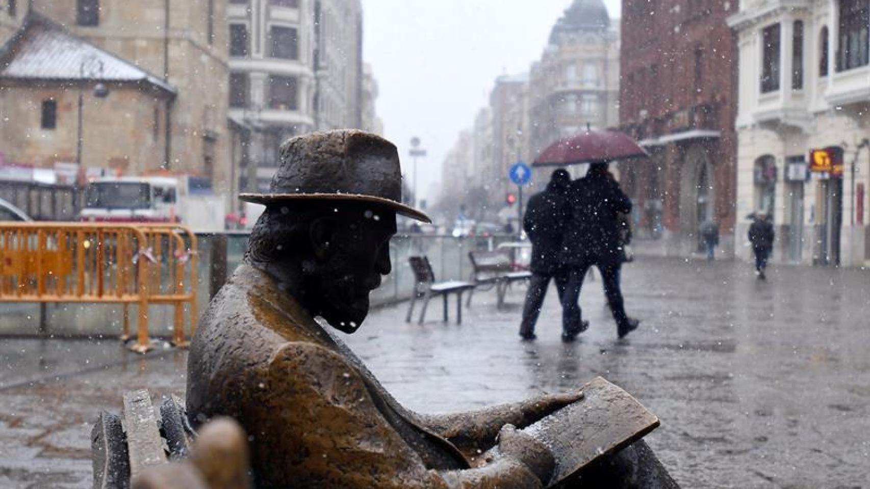 En primer plano, una escultura en León sufriendo una copiosa nevada.