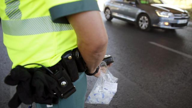 Un agente de la Guardia Civil sostiene una bolsa con boquillas para el control de alcolhemia y drogas.