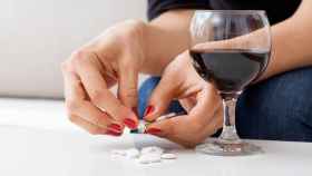 Una persona dispuesta a tomarse una copita de vino junto con algunos medicamentos.
