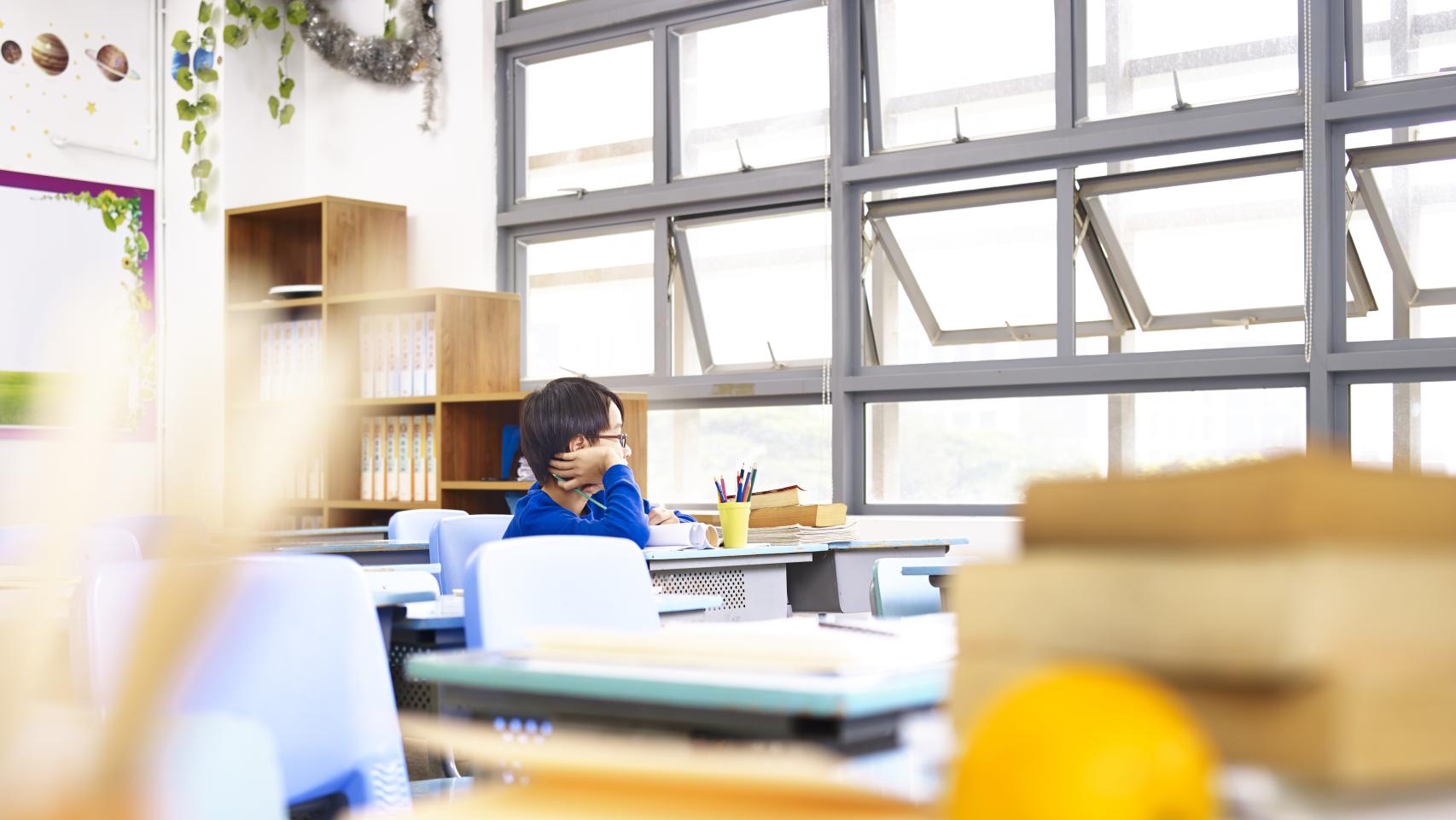 Un niño, solo, en una clase.