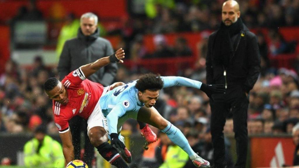 Valencia y Sané disputan un balón bajo la mirada Mourinho y Guardiola. Foto Twitter (@ManCity)