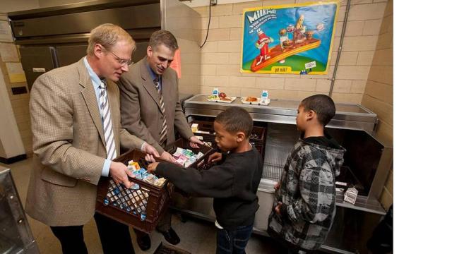 Brian Wansink (a la izquierda) entrega alimentos a unos niños