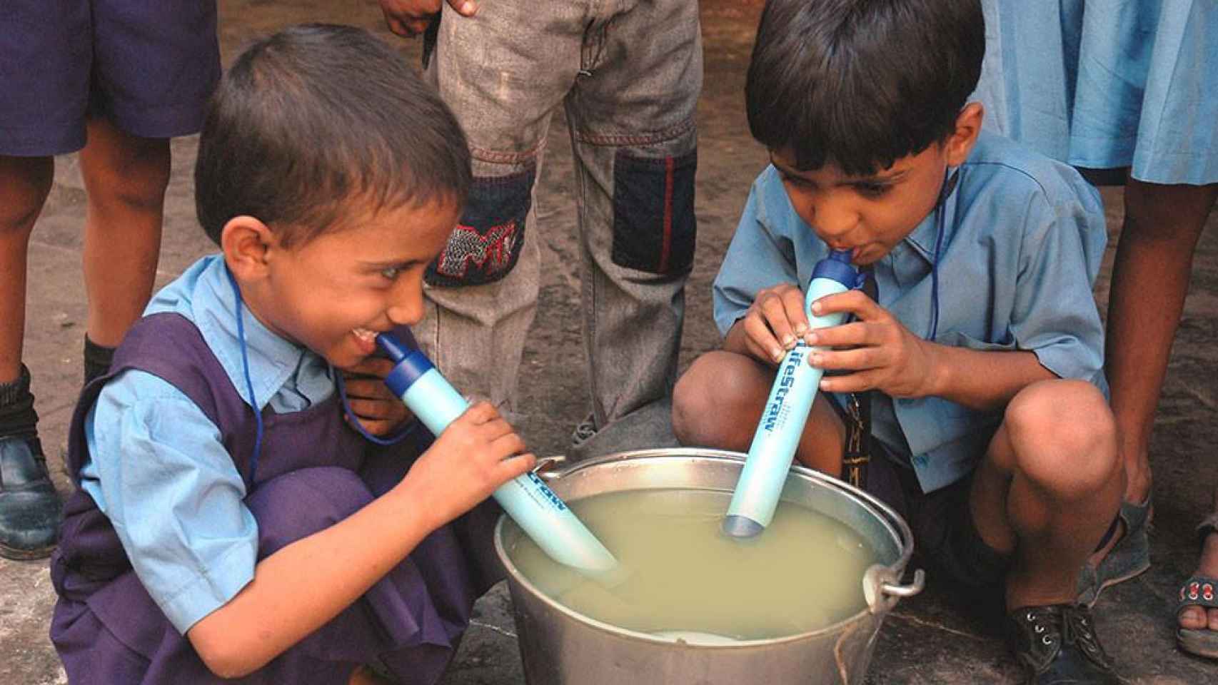 Unos niños usando LifeStraw en agua sucia.
