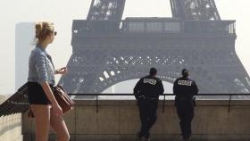 Una turista junto a dos policías en la Torre Eiffel