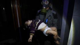 Un miembro de un equipo de rescate sujeta el cadáver de un niño tras el ataque químico en Duma.
