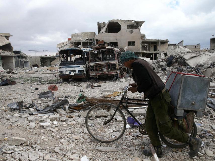 Un hombre camina con su bicicleta entre los escombros de Duma, en Siria.