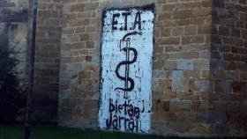 La puerta de una iglesia con una pintada de ETA.