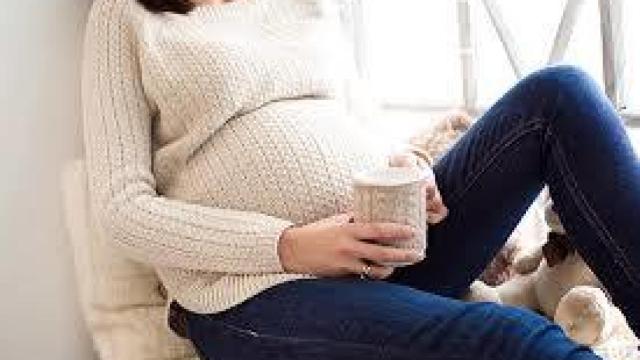 Una mujer embarazada, con una taza de café.