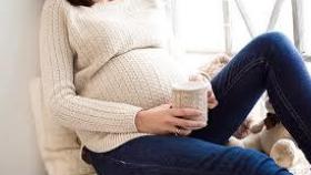 Una mujer embarazada, con una taza de café.