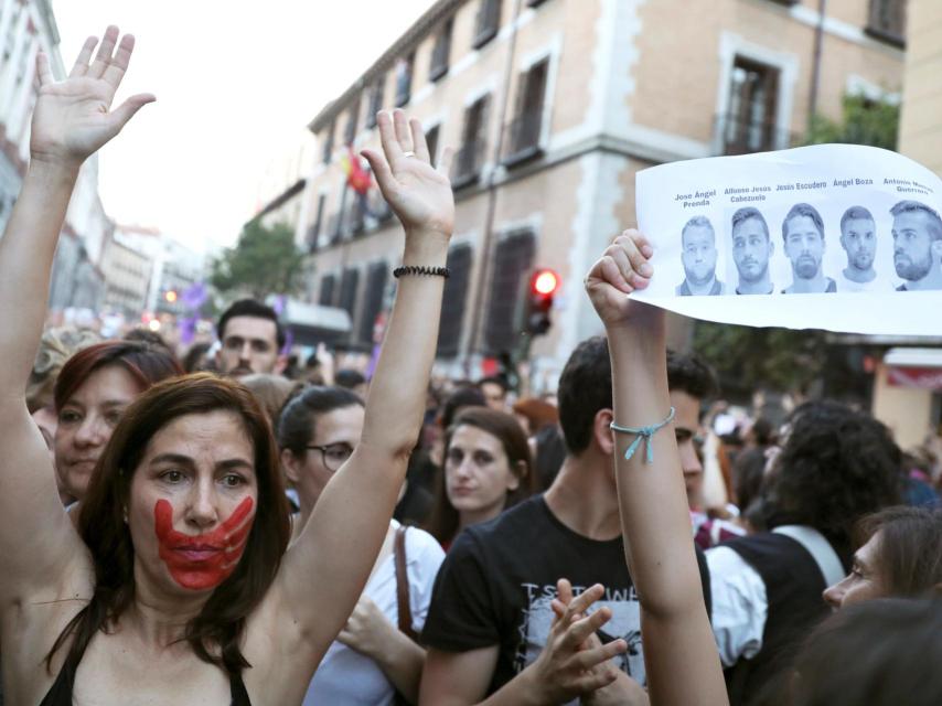 Una mujer con una marca de una mano en la cara levanta los brazos.