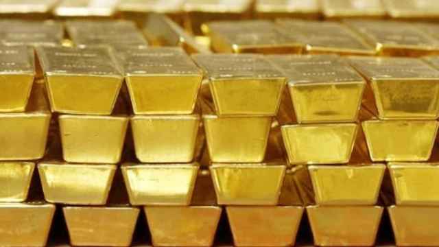 Varios lingotes de oro apilados en un depósito.