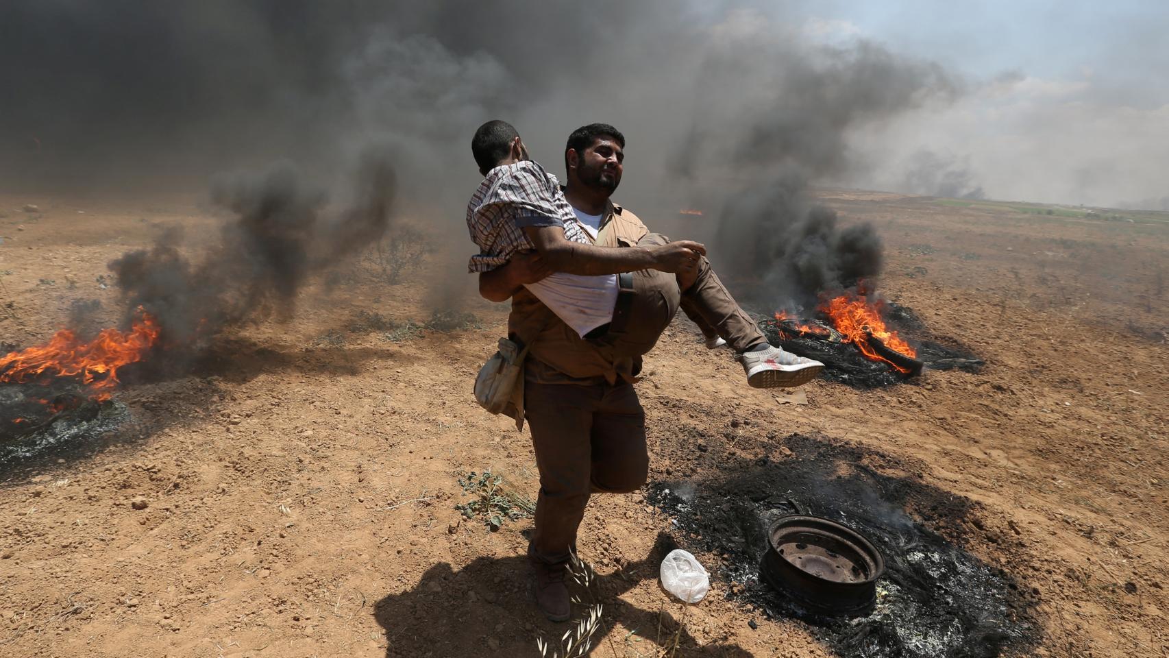 Un hombre carga con uno de los heridos en la frontera de Gaza.