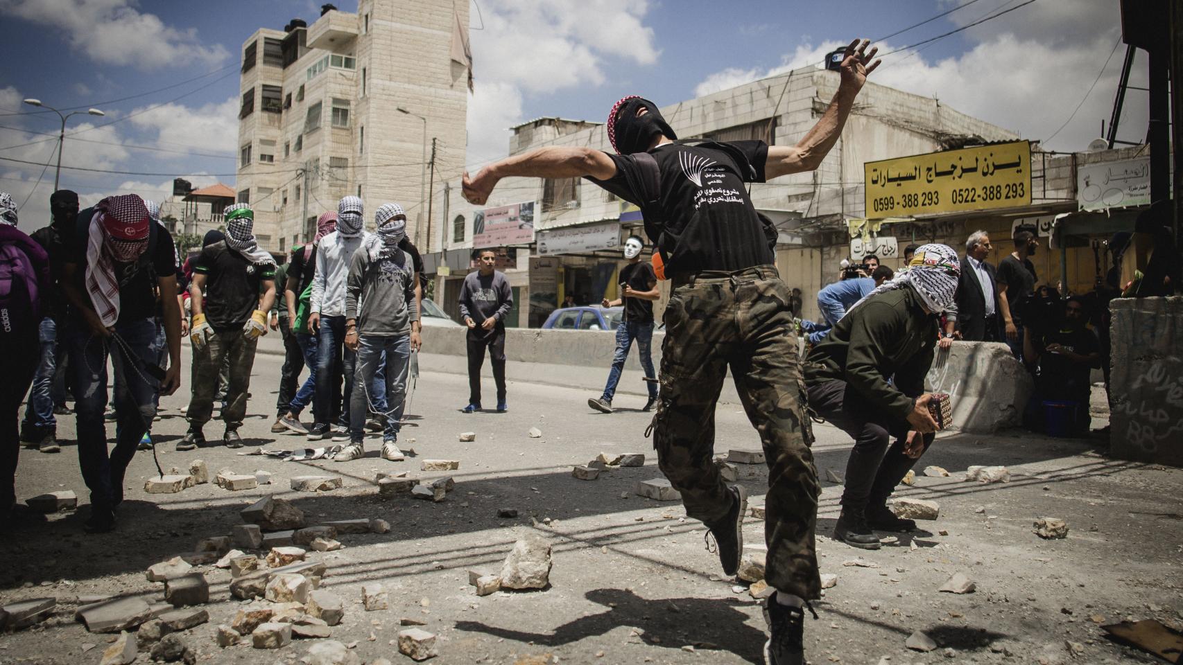 Un grupo de manifestantes palestinos lanza piedras durante los enfrentamientos.