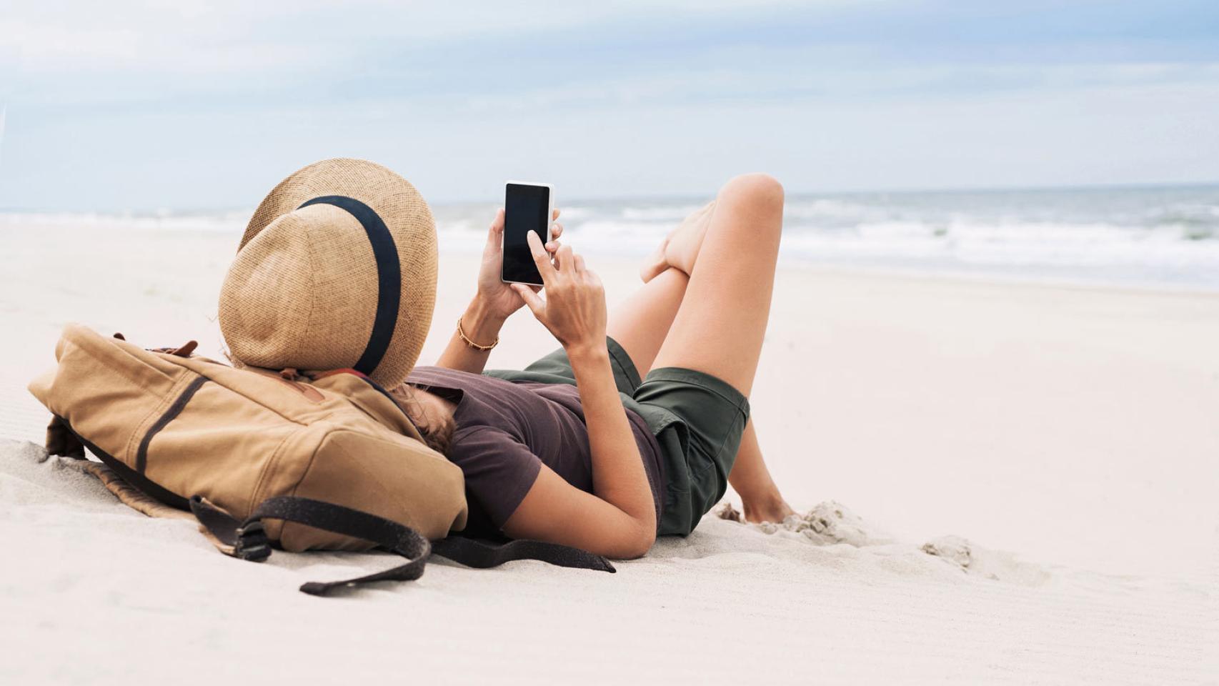 Una trabajadora contesta una llamada de la empresa en la playa.