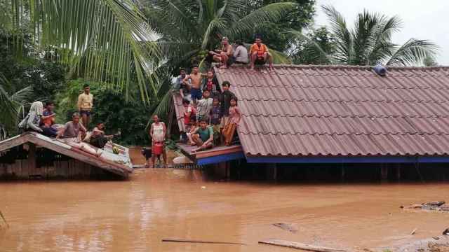 Varias personas en el tejado de una casa tras las inundaciones.