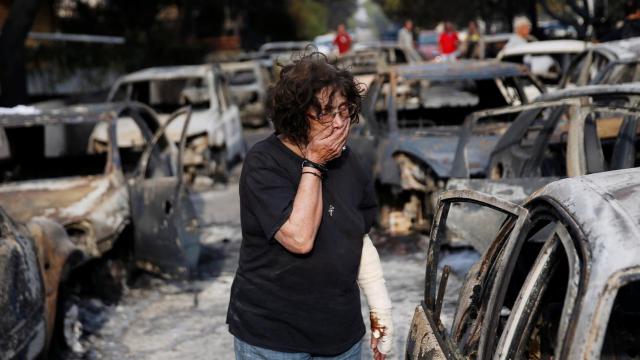 Una mujer llorando en medio de los coches calcinados.