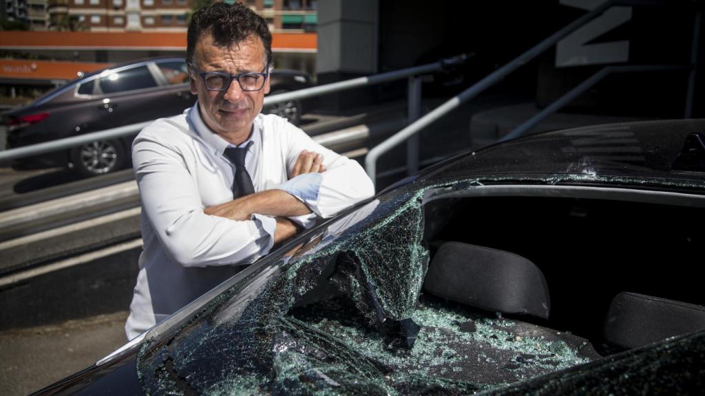 Rafael Navarro, chófer de Cabify en Barcelona, posando ante uno de los vehículos siniestrados.