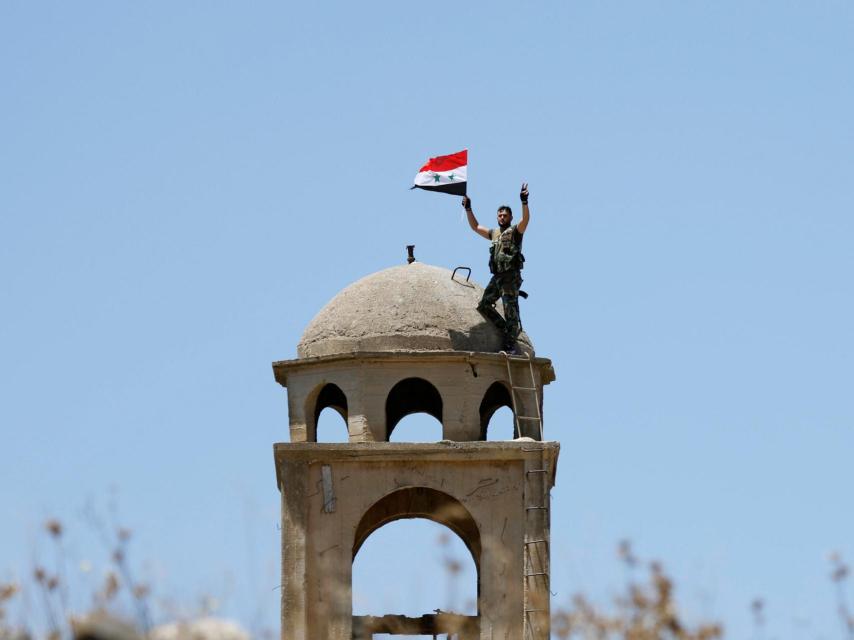 Un soldado sirio enarbola la bandera de su país.