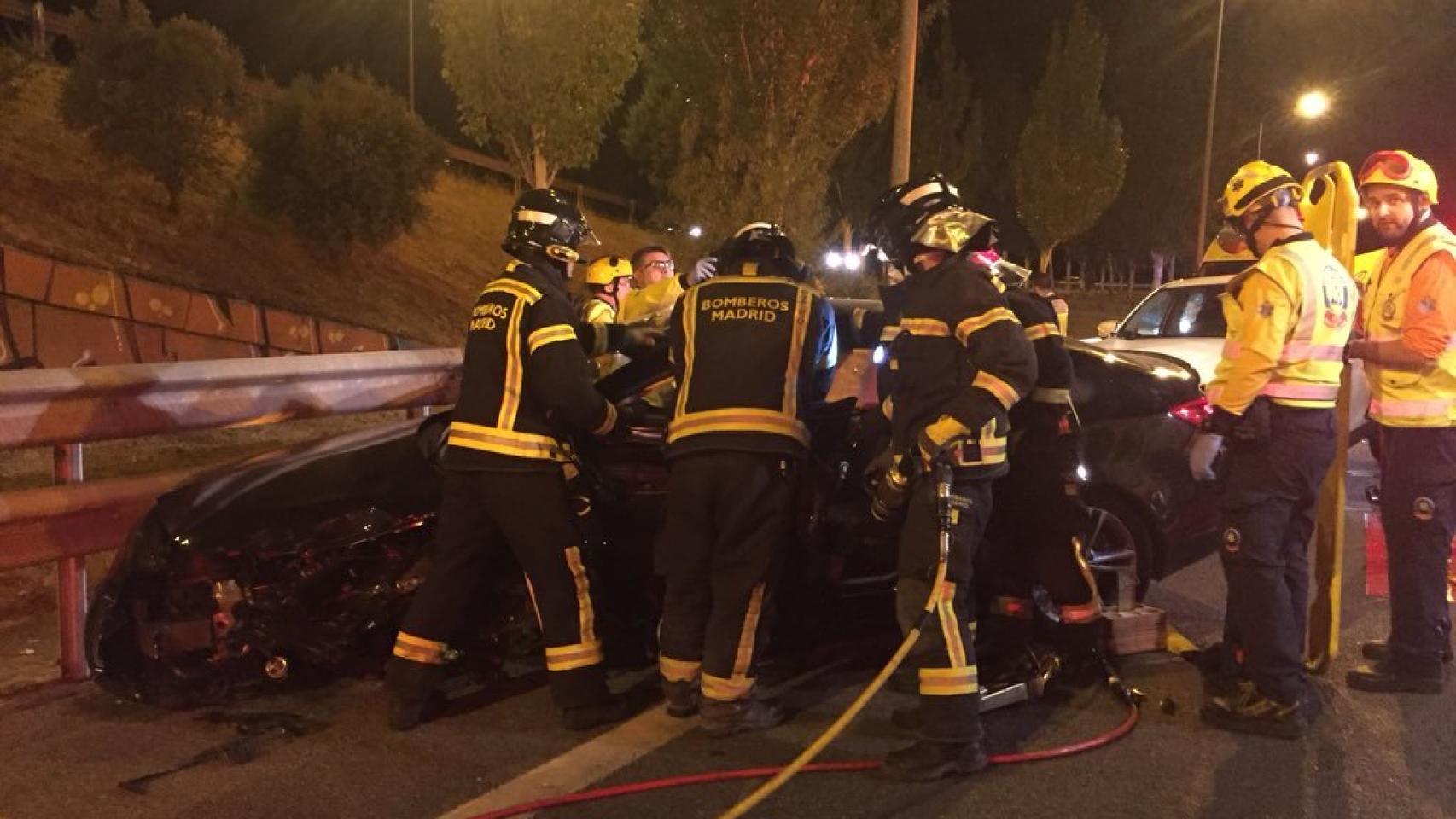 Los bomberos tratan de liberar a uno de los afectados en el accidente