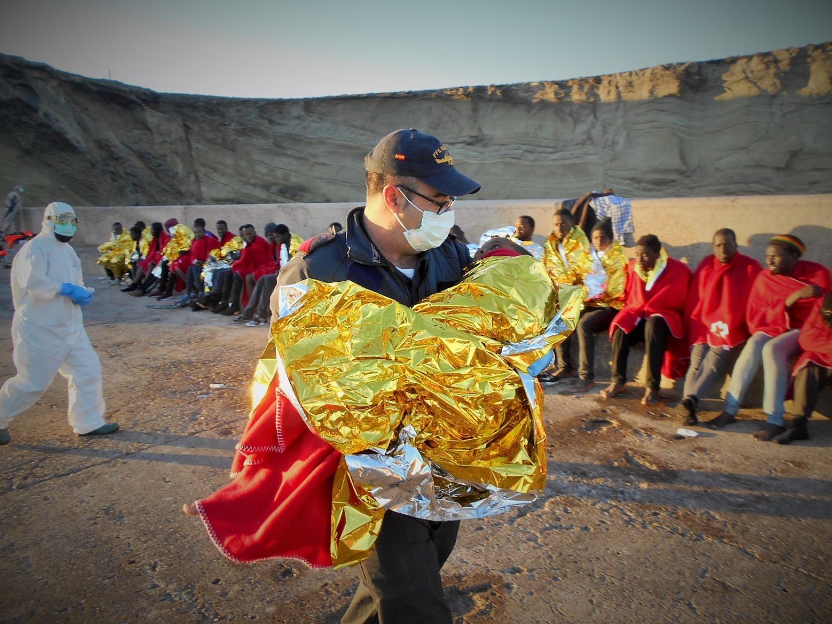 Un efectivo de la Armada atiende a un niño a su llegada a la isla de Alborán.