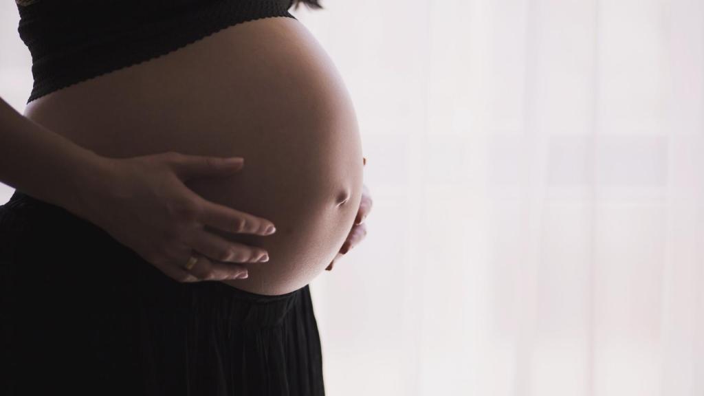 Una mujer embarazada toca su barriga.